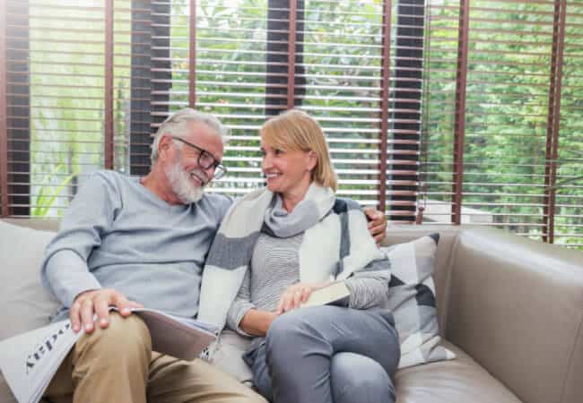 elderly couple happily sitting together on a couch